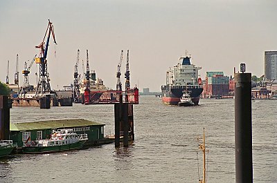 Et stort containerskib trkkes til kaj af et par slbebde